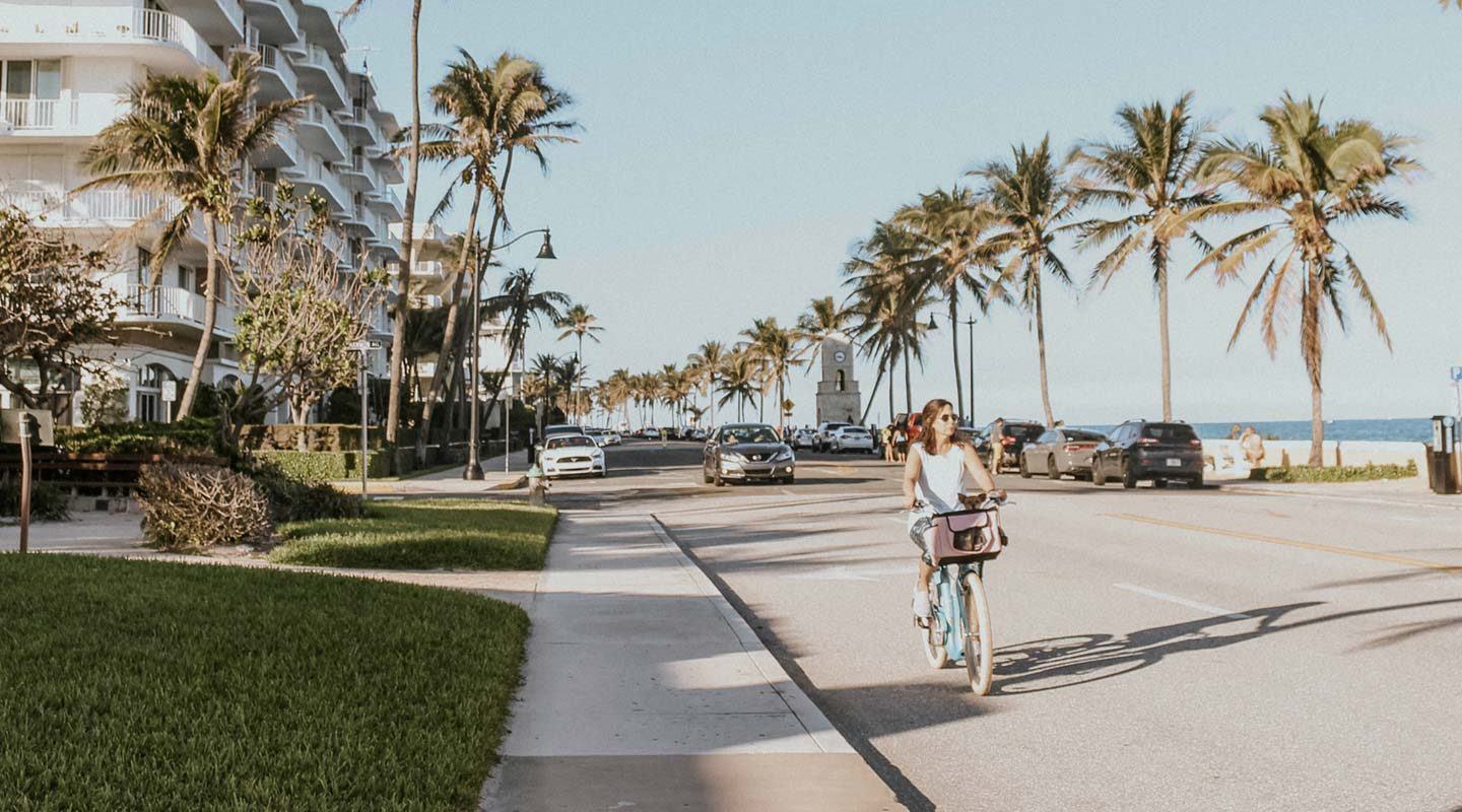 a woman wearing sunglasses biking along the beach