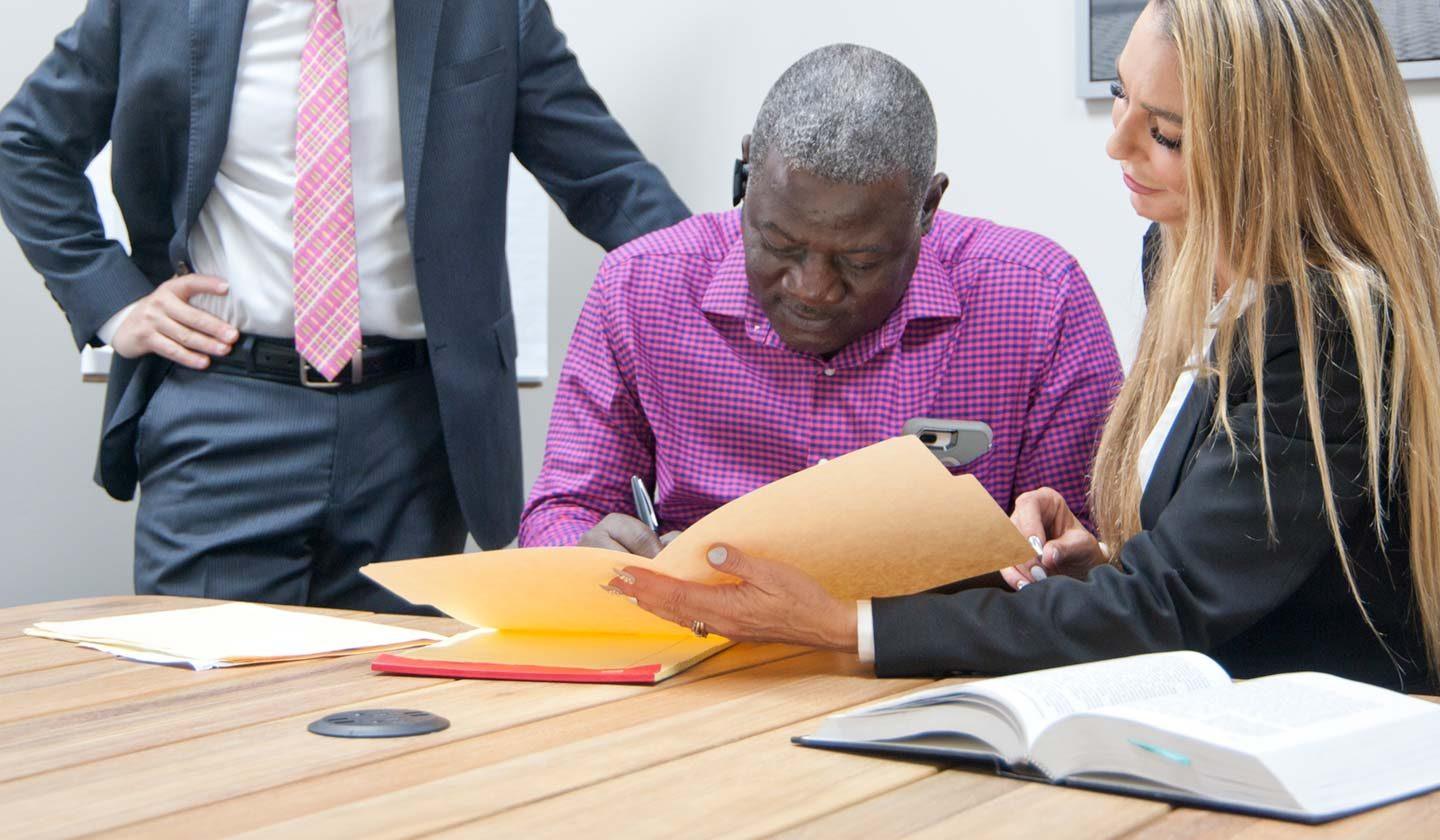 Steve and Kerri Deitsch sitting with a client signing paper work